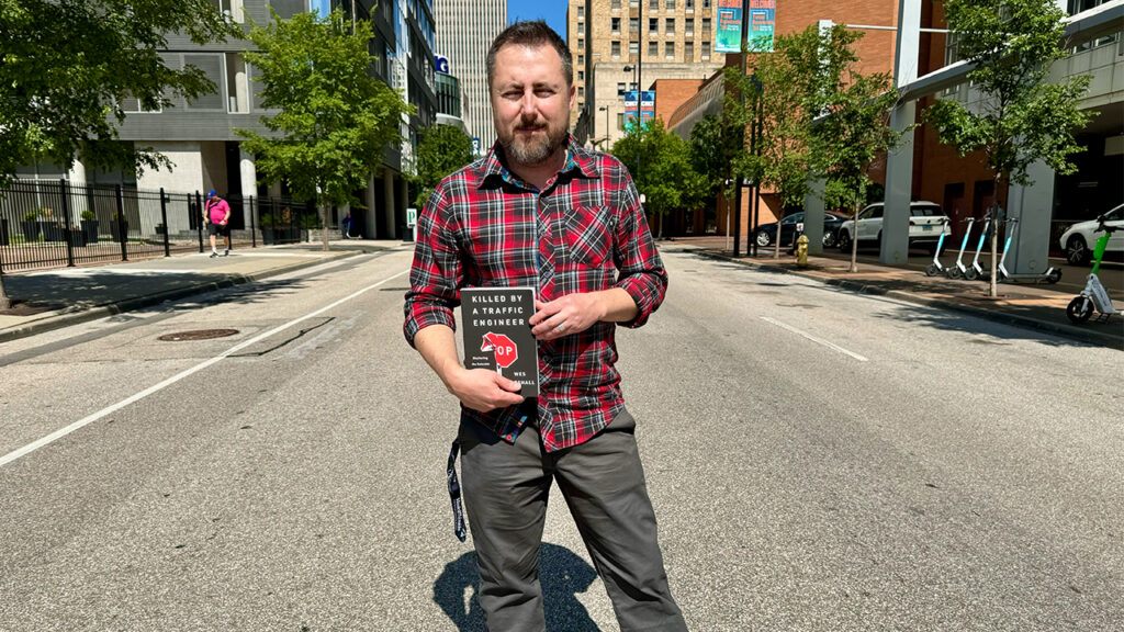 Man holding a book in the middle of a wide street